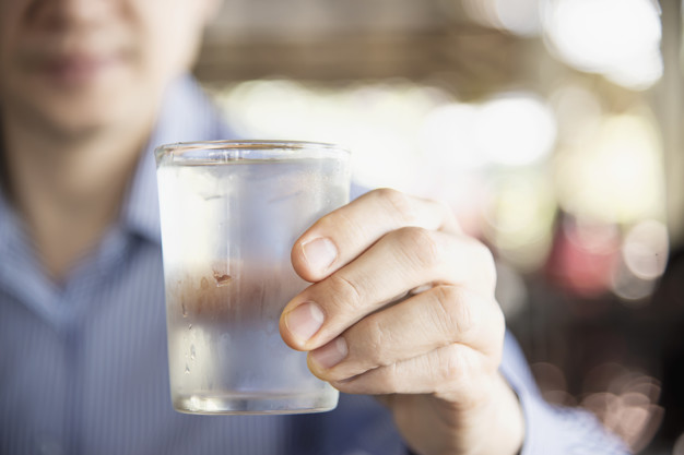 Hombre tomando agua de dispensadores de agua fria